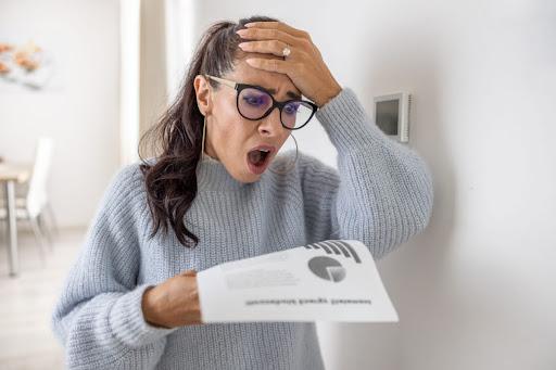 A woman with a shocked expression looking at a bill.